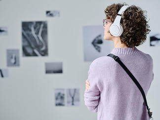 Museumsbesucherin betrachtet Ausstellung mit einem Audioguide